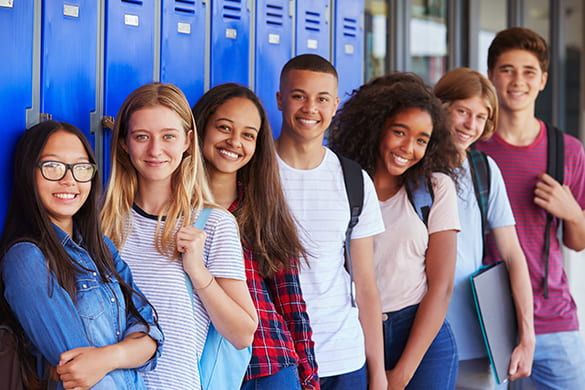 A lineup of students smile with backpacks