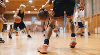 A youth basketball team practices dribbling on an indoor court