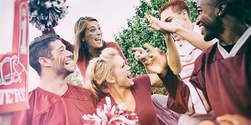 A group of sports fans cheer at a tailgate