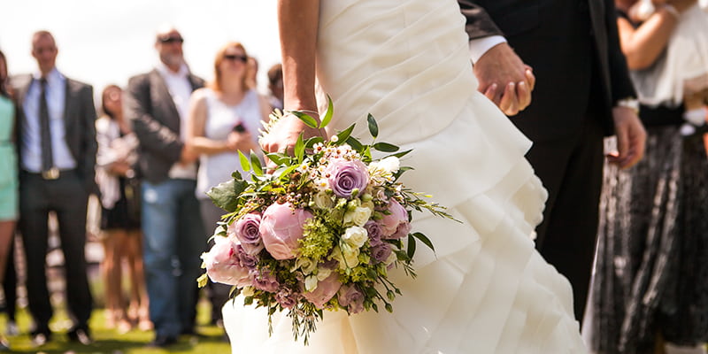 A bride and groom hold hands at an outdoor wedding